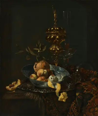 Ein vergoldeter Becher mit Deckel, ein Römer, ein Glas im Façon-de-Venise-Stil, Pfirsiche, Orangen und eine geschälte Zitrone in einer Porzellanschale auf einem teilweise bedeckten Tisch von Willem Kalf