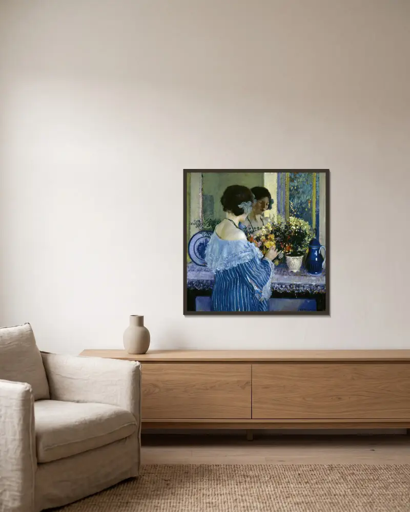 Flicka i blått ordnar blommor av Frederick Carl Frieseke inramad på en vägg