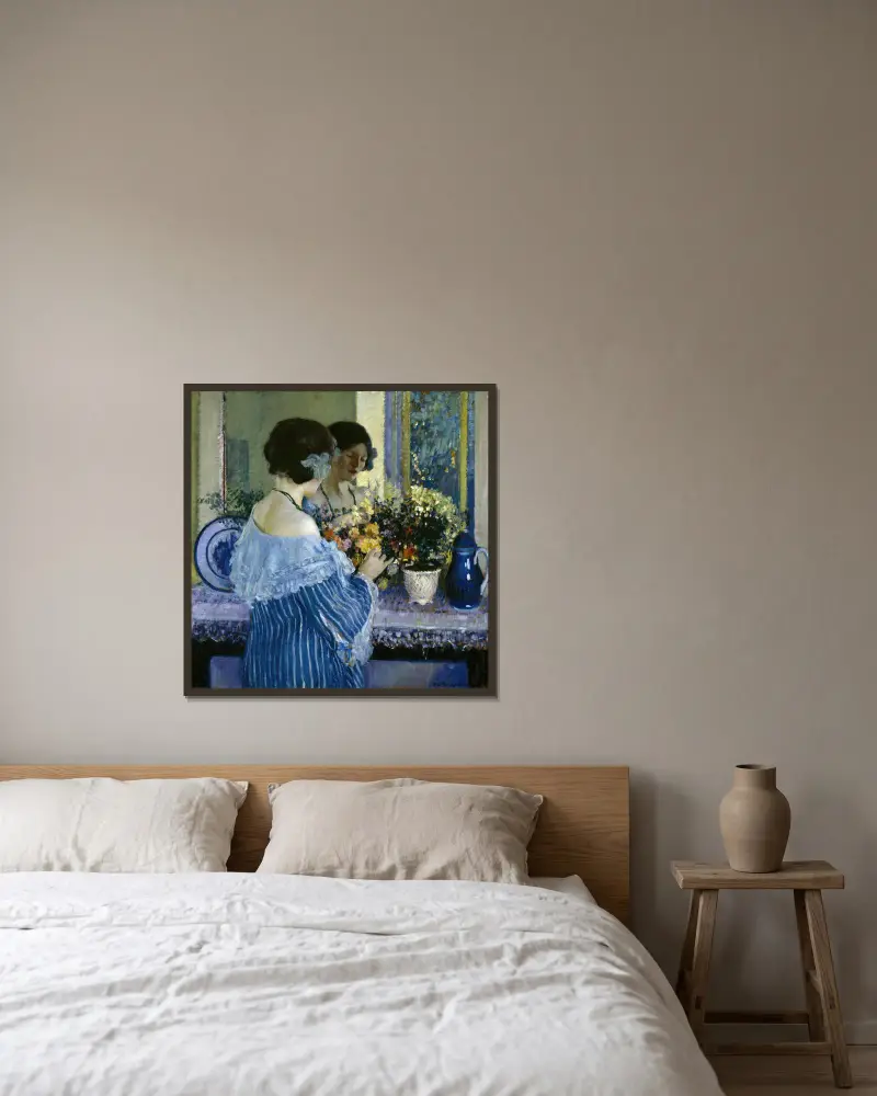 Flicka i blått ordnar blommor av Frederick Carl Frieseke inramad på en vägg