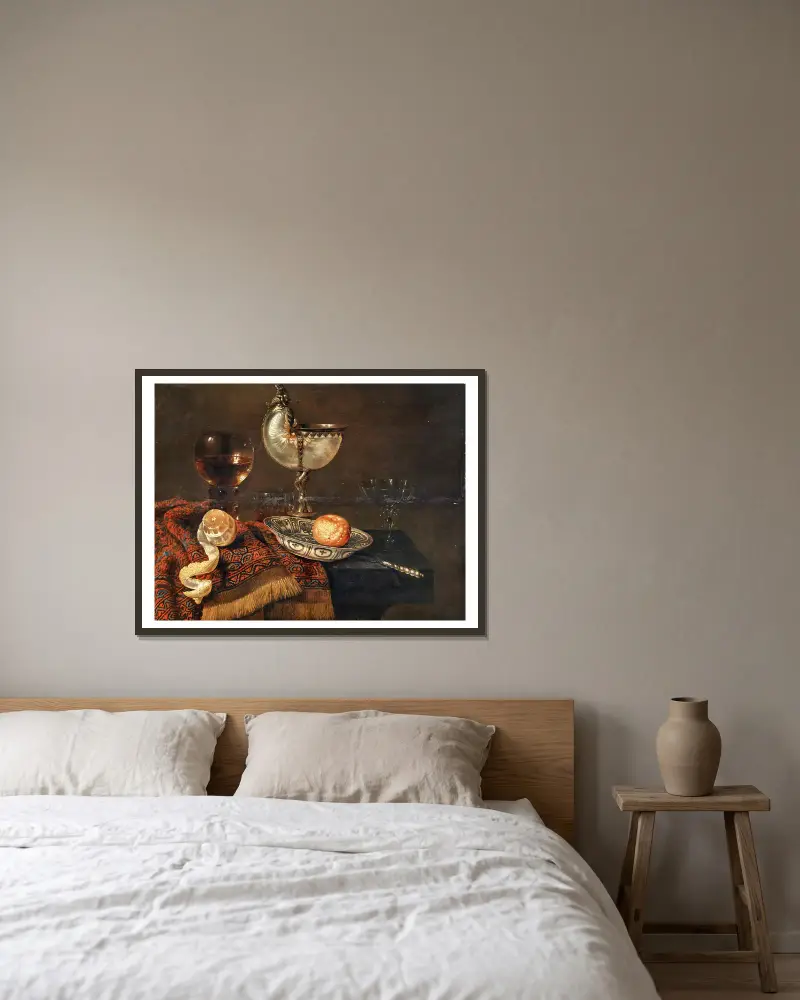 En klementin i en porslinsskål, en nautiluspokal, ett roemer, två glas, en kniv, en skalad citron på en prydnadsmatta på ett bord av Willem Claesz Heda inramad på en vägg