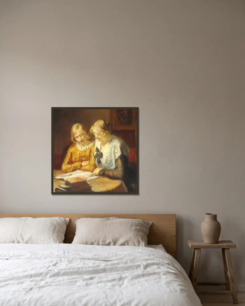Två unga flickor sitter vid bordet och läser i en bok av Michael Ancher inramad på en vägg