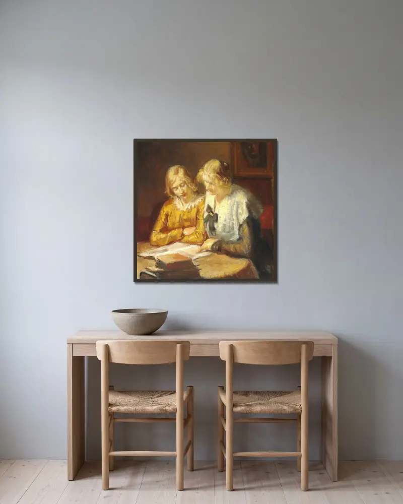 Två unga flickor sitter vid bordet och läser i en bok av Michael Ancher inramad på en vägg