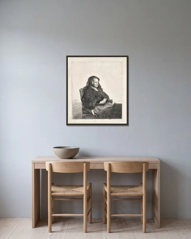 Die Mutter des Künstlers an einem Tisch sitzend, nach rechts blickend von Rembrandt van Rijn gerahmt an einer Wand