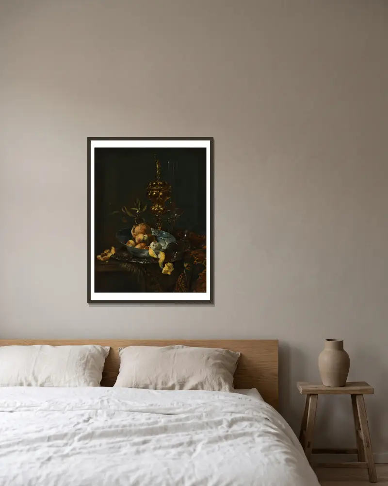 En förgylld bägare med lock, en roemer, ett glas i façon-de-venise-stil, persikor, apelsiner och en skalad citron i en porslinsskål på ett delvis draperat bord av Willem Kalf inramad på en vägg
